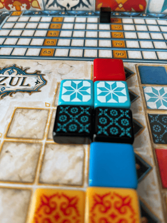 Eight square Azul Tiles on the game board, with a score marker in the background