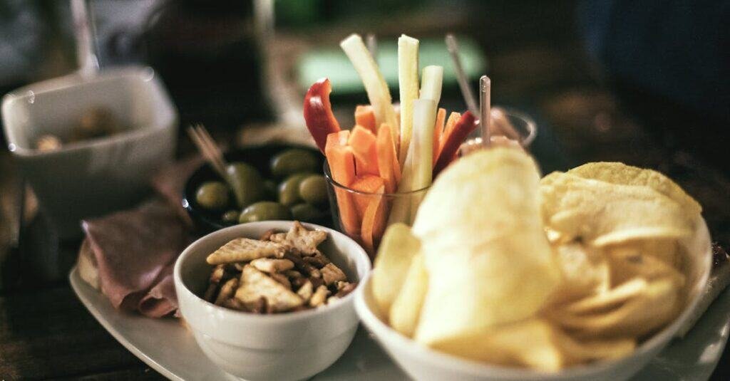 food-vegetables-italian-restaurant-1475 A tempting snack platter featuring crisps, vegetables, and olives, perfect for a casual gathering.
