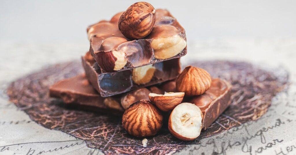 pexels-photo-1693027-1693027 Close-up of stacked chocolate bars with whole hazelnuts, perfect for sweet indulgence.