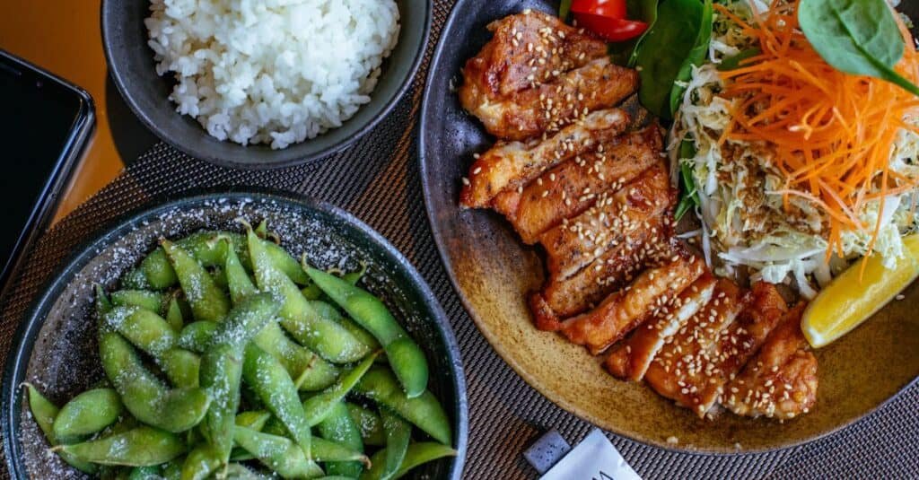 pexels-photo-1860207-1860207 A beautifully presented Japanese meal featuring teriyaki chicken, rice, salad, and edamame.