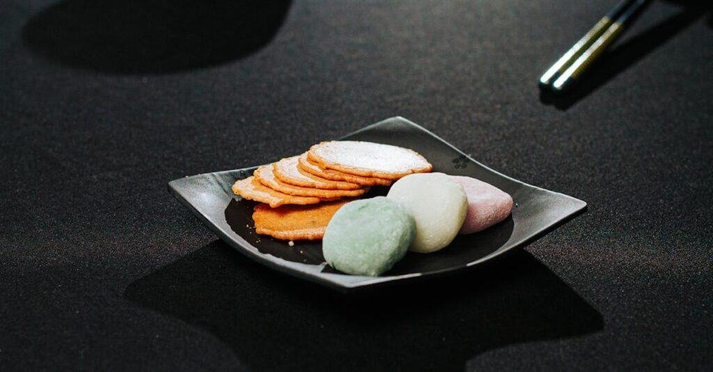 pexels-photo-31302303-31302303 Colorful mochi and rice crackers elegantly presented on a black plate, evoking Japanese culinary traditions.