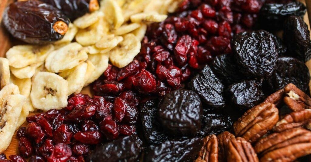pexels-photo-3872425-3872425 Vibrant mix of dried fruits and nuts on a wooden tray, perfect for healthy snacking.